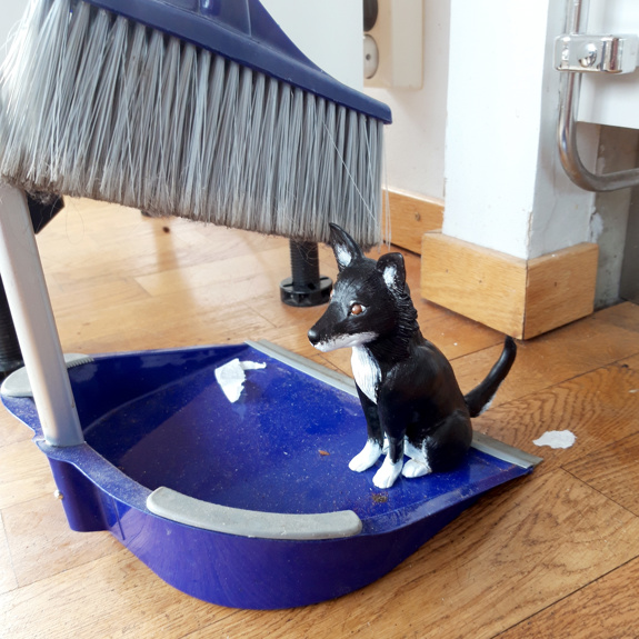 Hunden står vid en sop.